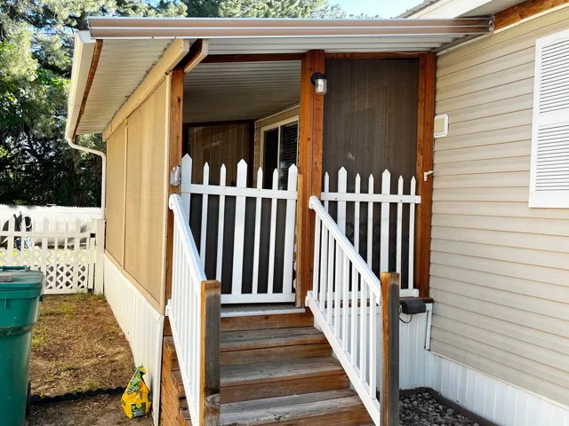 Screened porch entry with wood steps and white picket fence railing