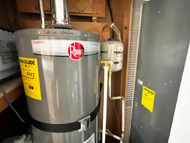 Rheem water heater with expansion tank and associated plumbing, accompanied by a furnace unit