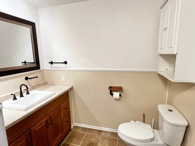 Bathroom featuring a wood-finish vanity with a light-toned countertop and integrated sink