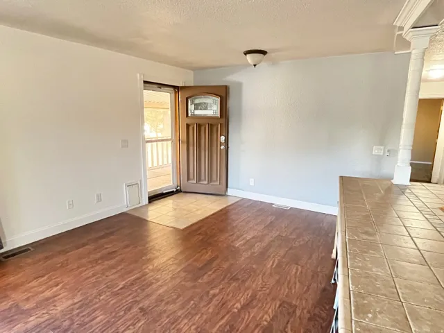 Entryway featuring a decorative wood-panel door with an arched glass insert, tiled landing, and wood-finish flooring
