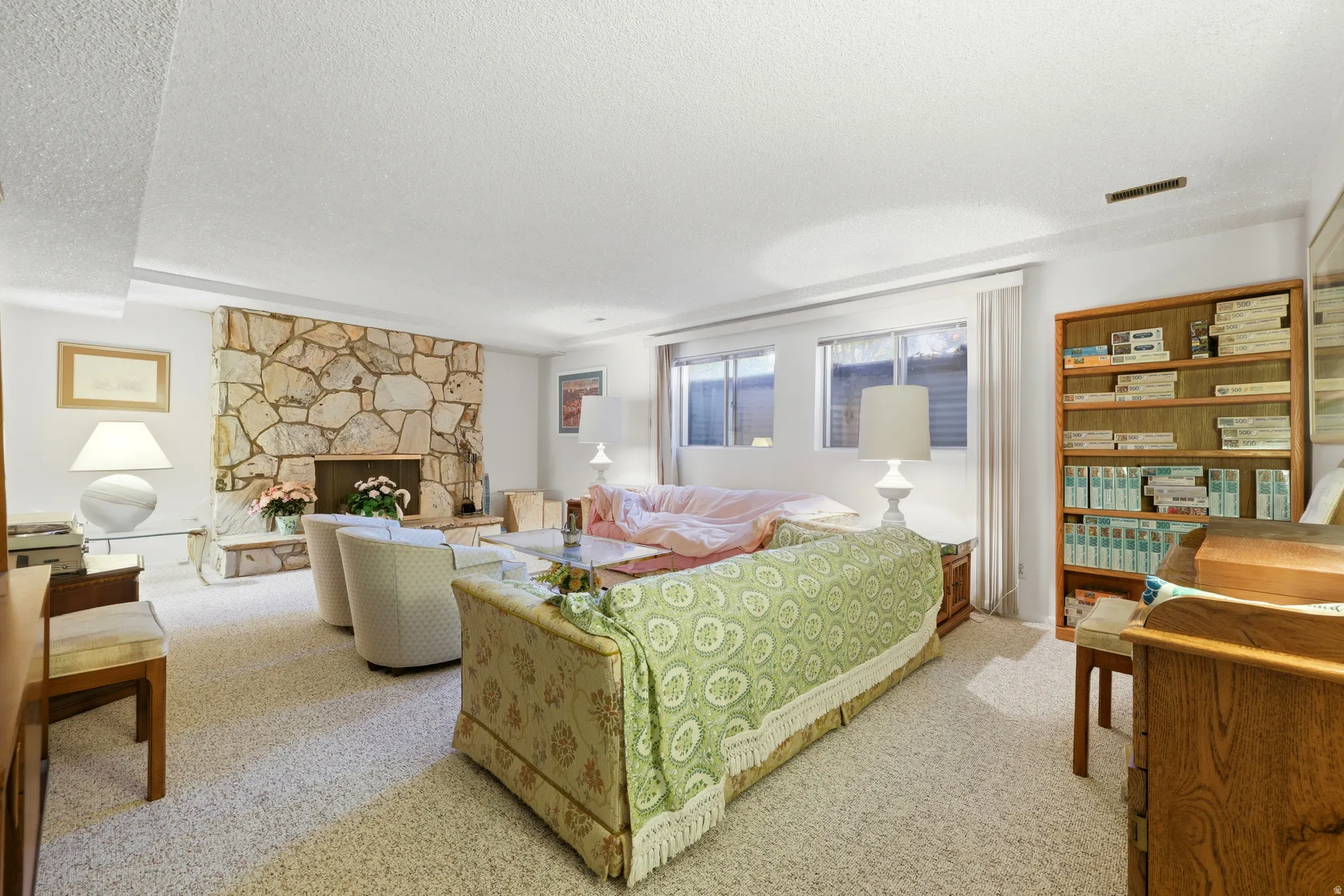 Living area featuring a stone fireplace, recessed lighting, and soft carpet flooring