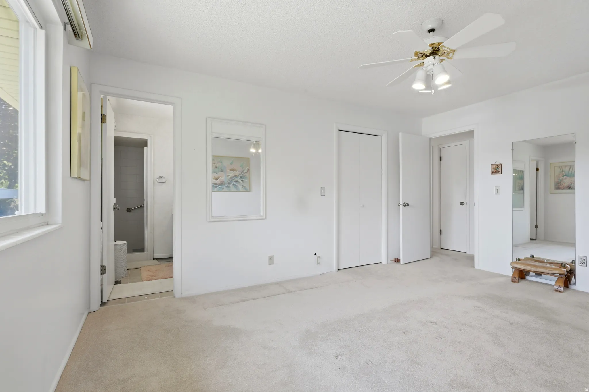 Carpeted interior with light-colored walls, featuring a ceiling fan with light fixture