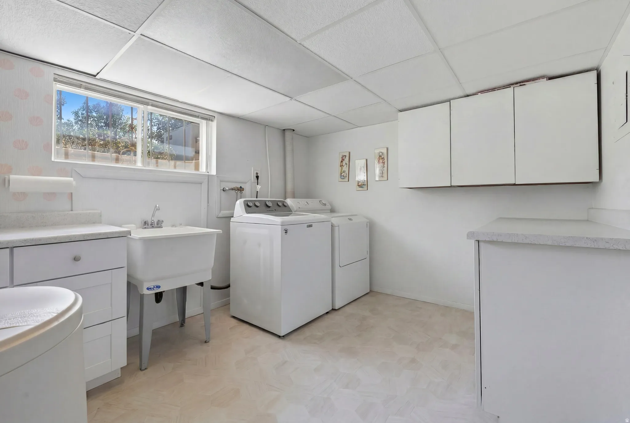 Dedicated laundry space featuring a utility sink, a window, built-in cabinetry, and countertop space