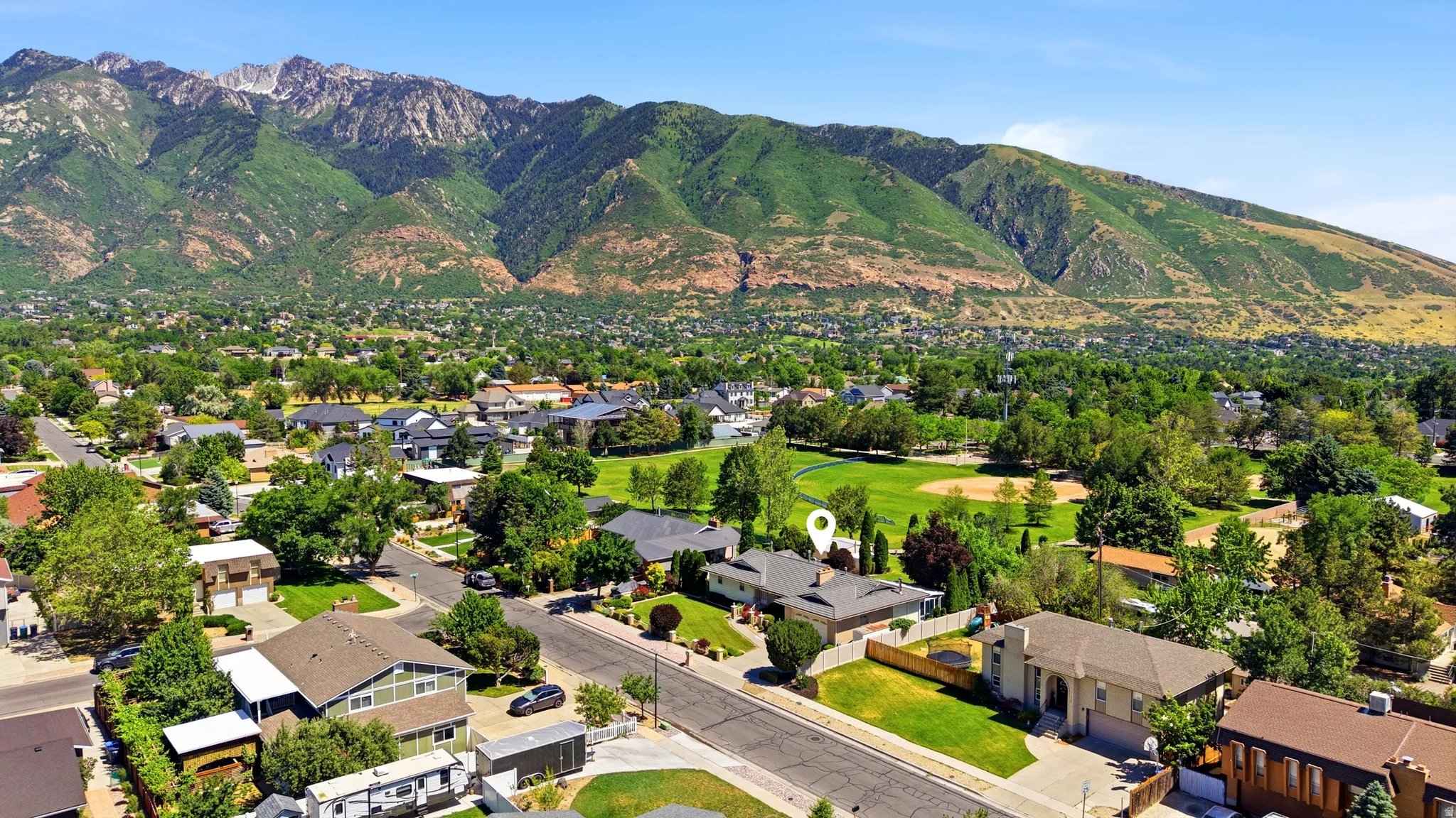 Neighborhood setting with mature trees, green spaces, and mountain backdrop