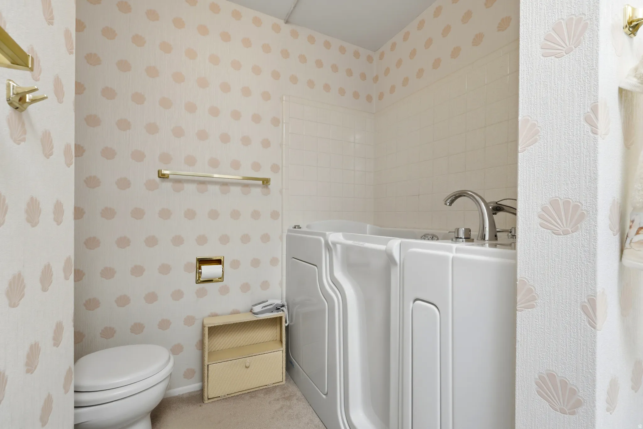 Bathroom featuring a walk-in tub with chrome fixtures, a white toilet, and textured wallpaper