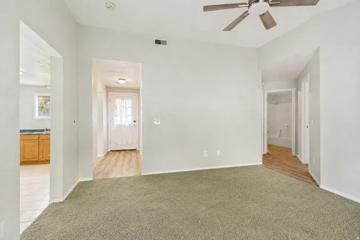 Vaulted family room looking back to entry, with kitchen on one side and hall to two bedrooms and bath on the other.