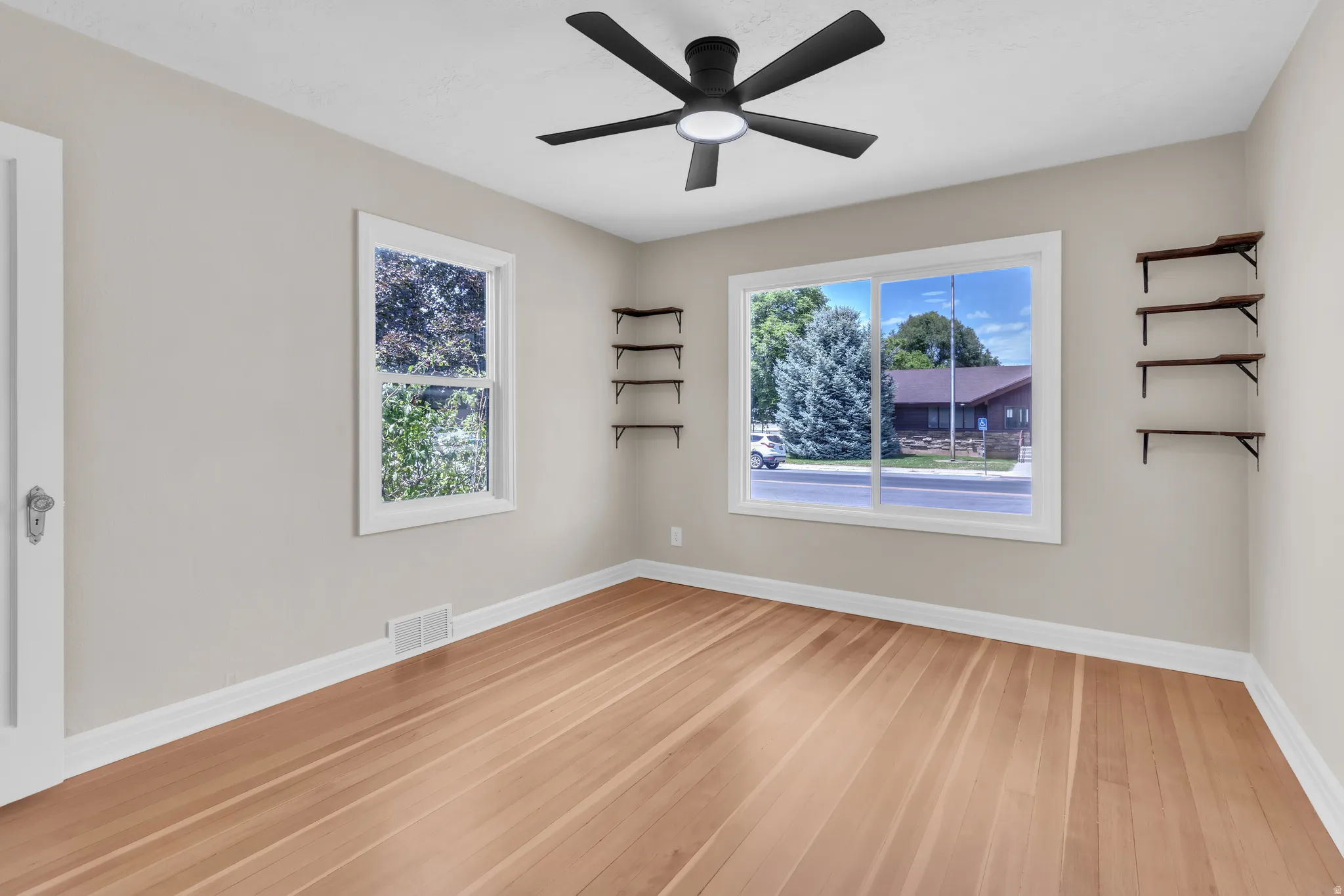 Spacious room featuring light wood-finish flooring, neutral wall paint, and white trim
