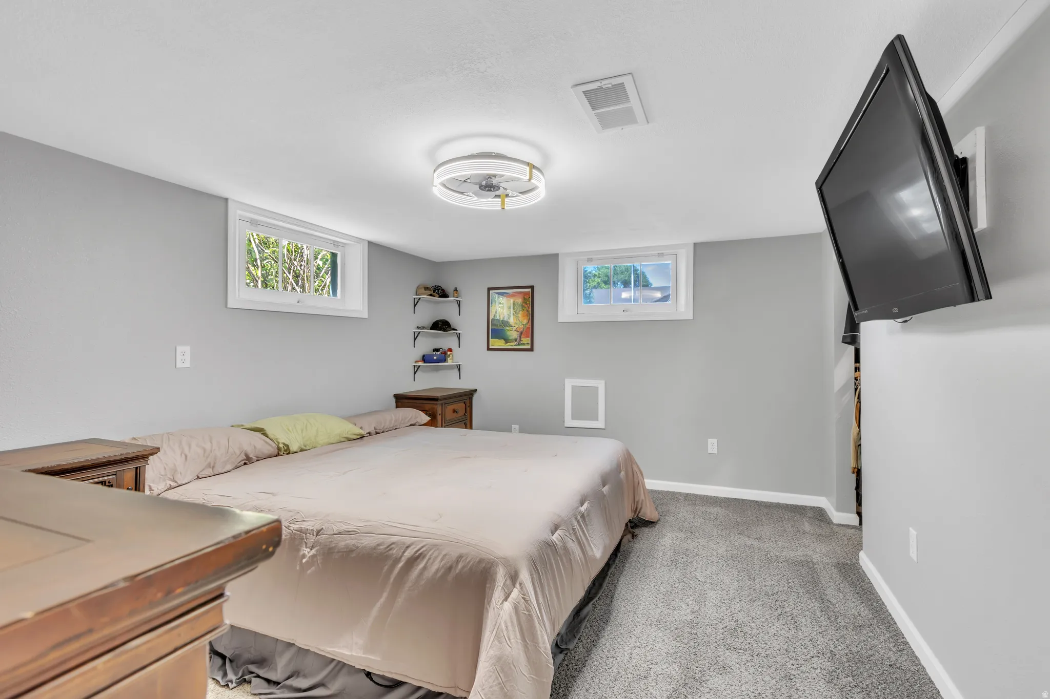 Bedroom featuring two windows, neutral gray wall tones, and gray carpeting