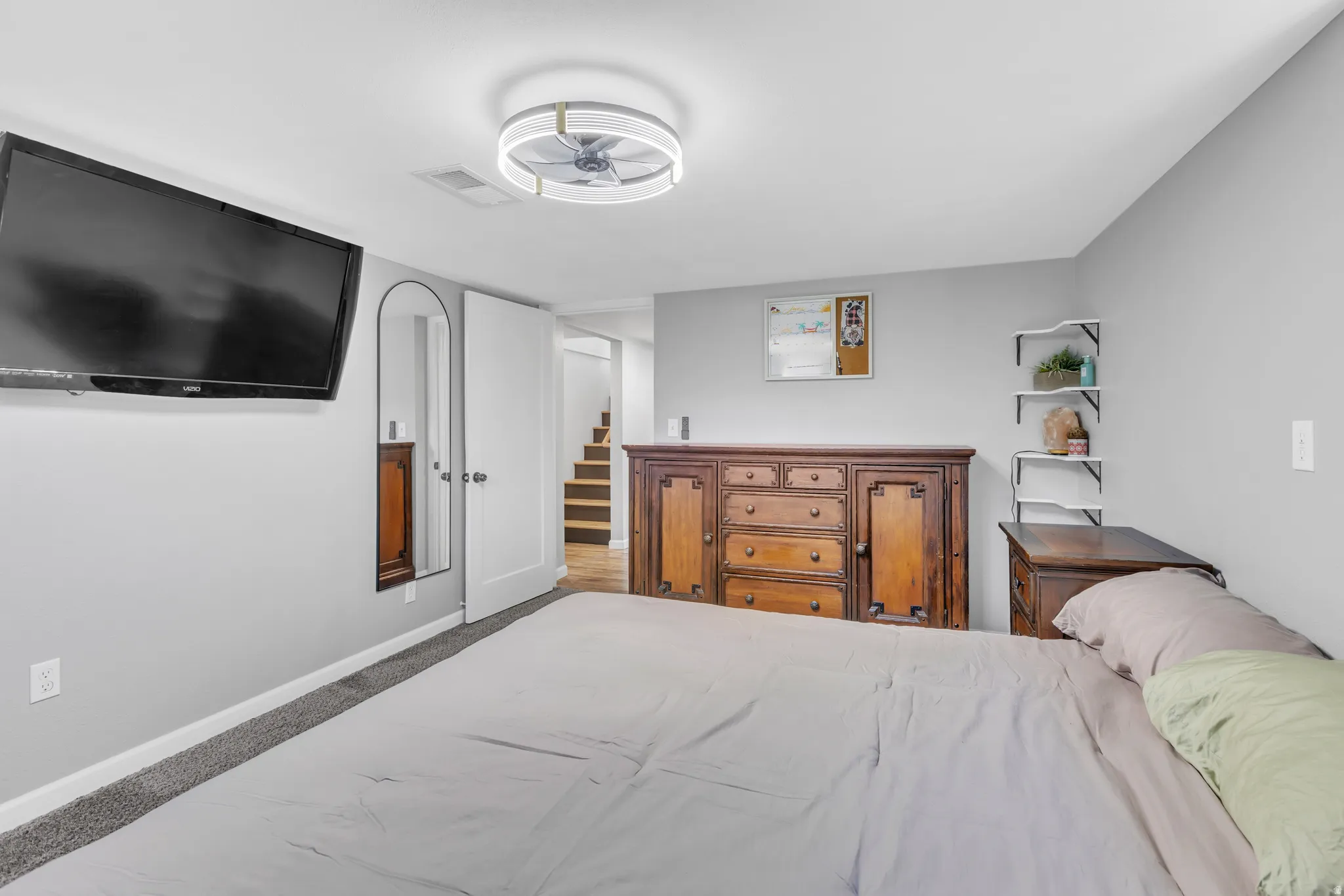 Spacious room featuring light gray wall paint, a ceiling-mounted fan fixture, and a white door frame