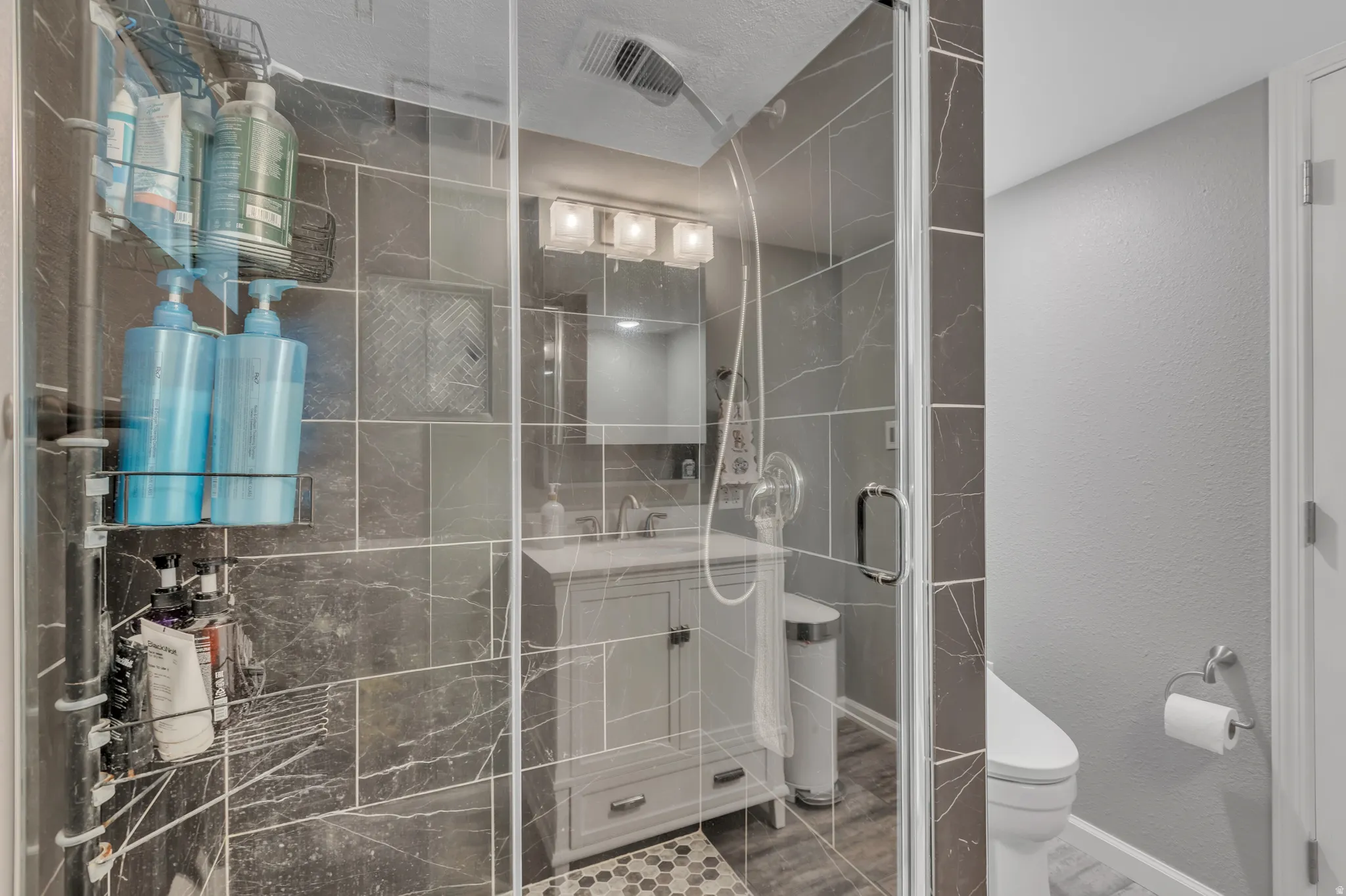 Modern bathroom featuring a glass-enclosed shower with dark tile surround