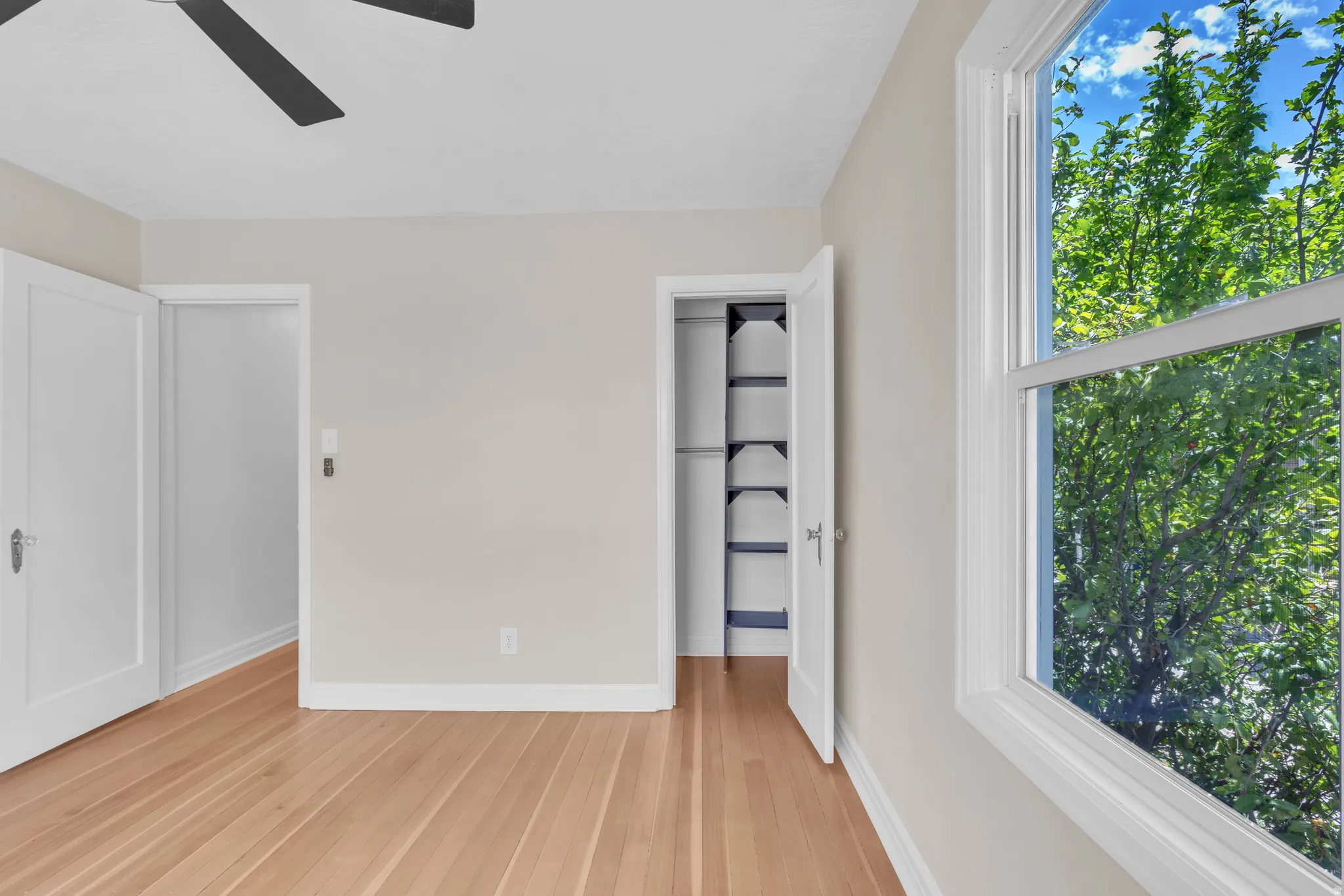 Room featuring wood-finish flooring, light-toned wall paint, white trim, and a white window frame