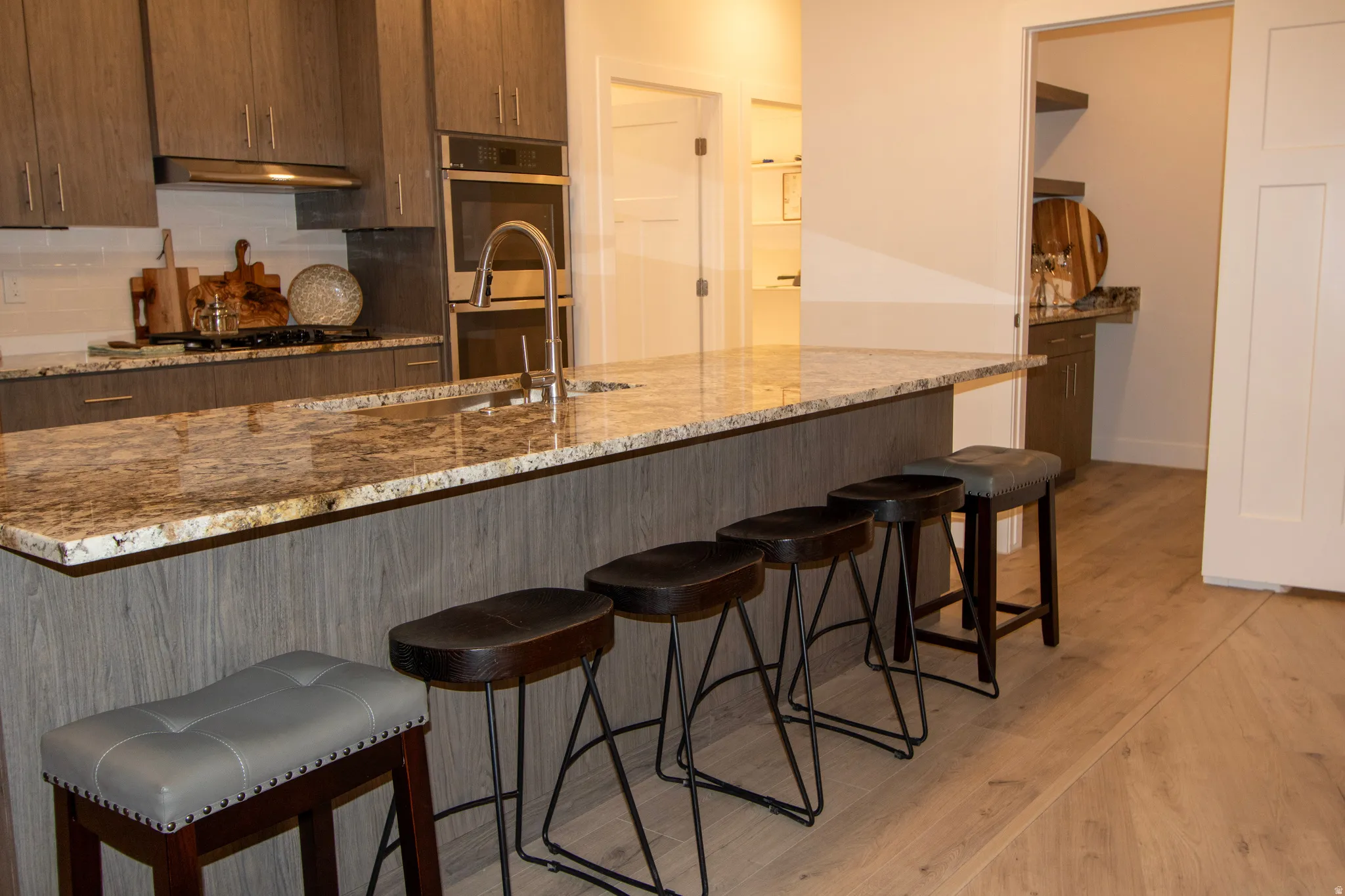 Kitchen island featuring an undermount sink, gooseneck faucet, and light-toned stone countertop