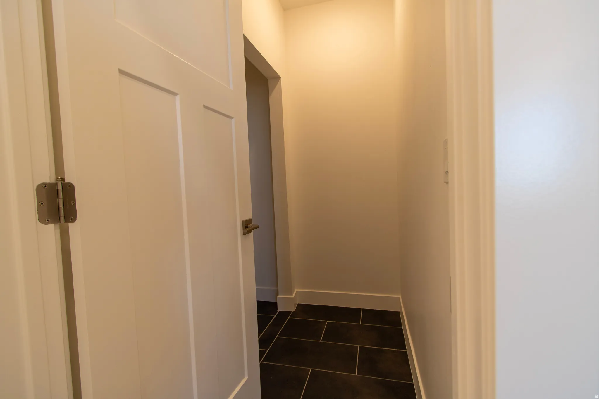 Hallway with dark rectangular tile flooring