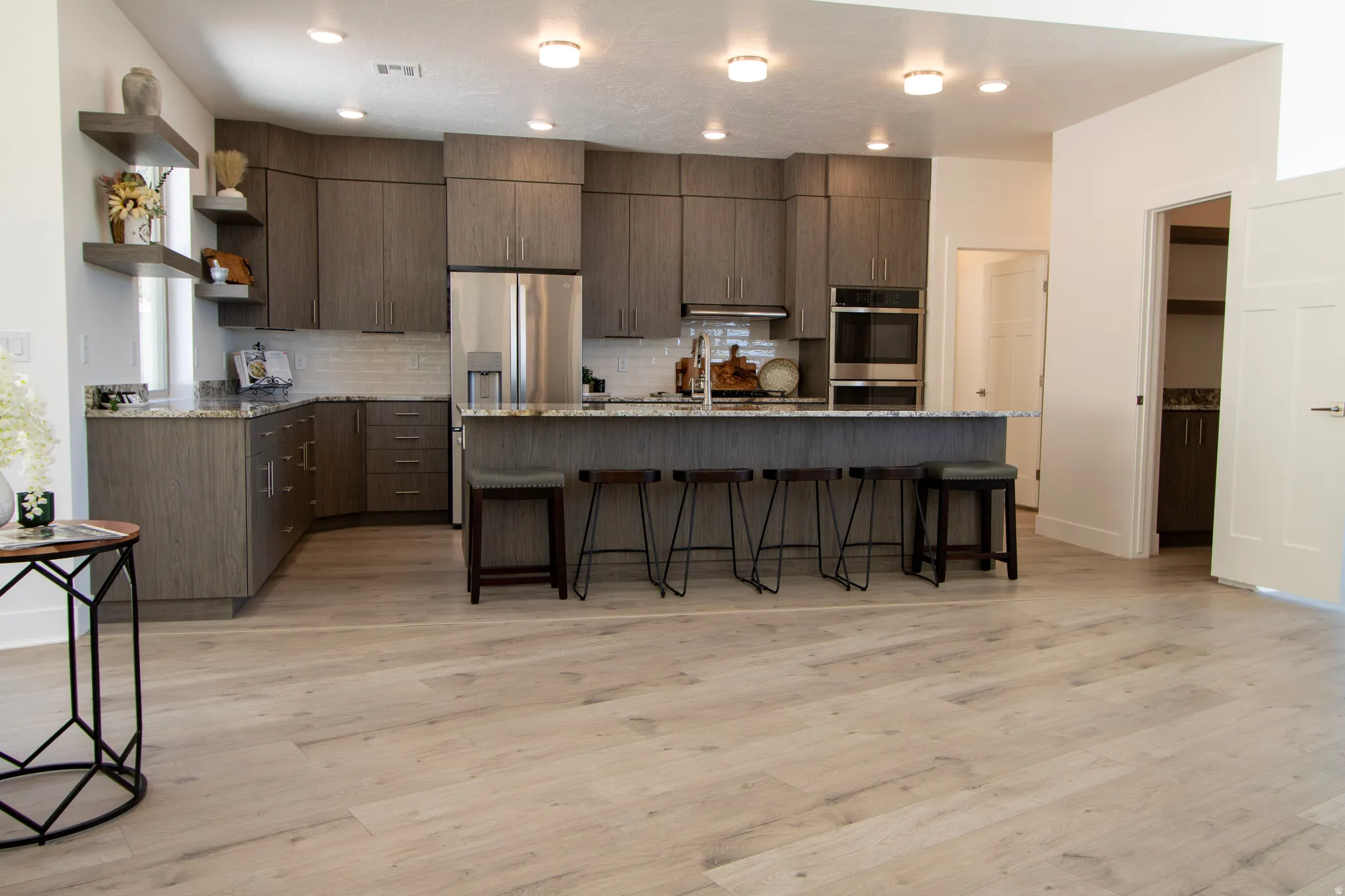 Modern kitchen featuring wood-finish cabinetry, stainless steel appliances, speckled stone countertops, and a white subway tile backsplash