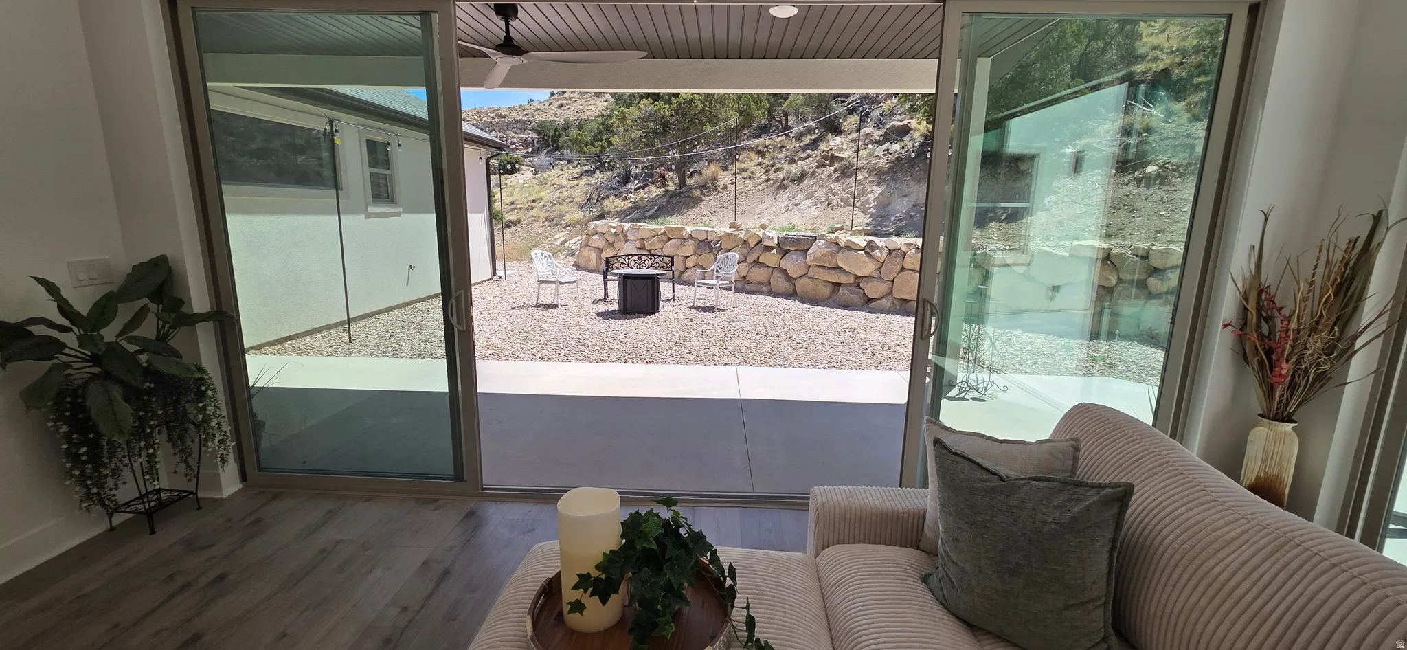 Sliding glass doors opening to an outdoor patio with a gravel hardscape, retaining wall, and natural rock elements