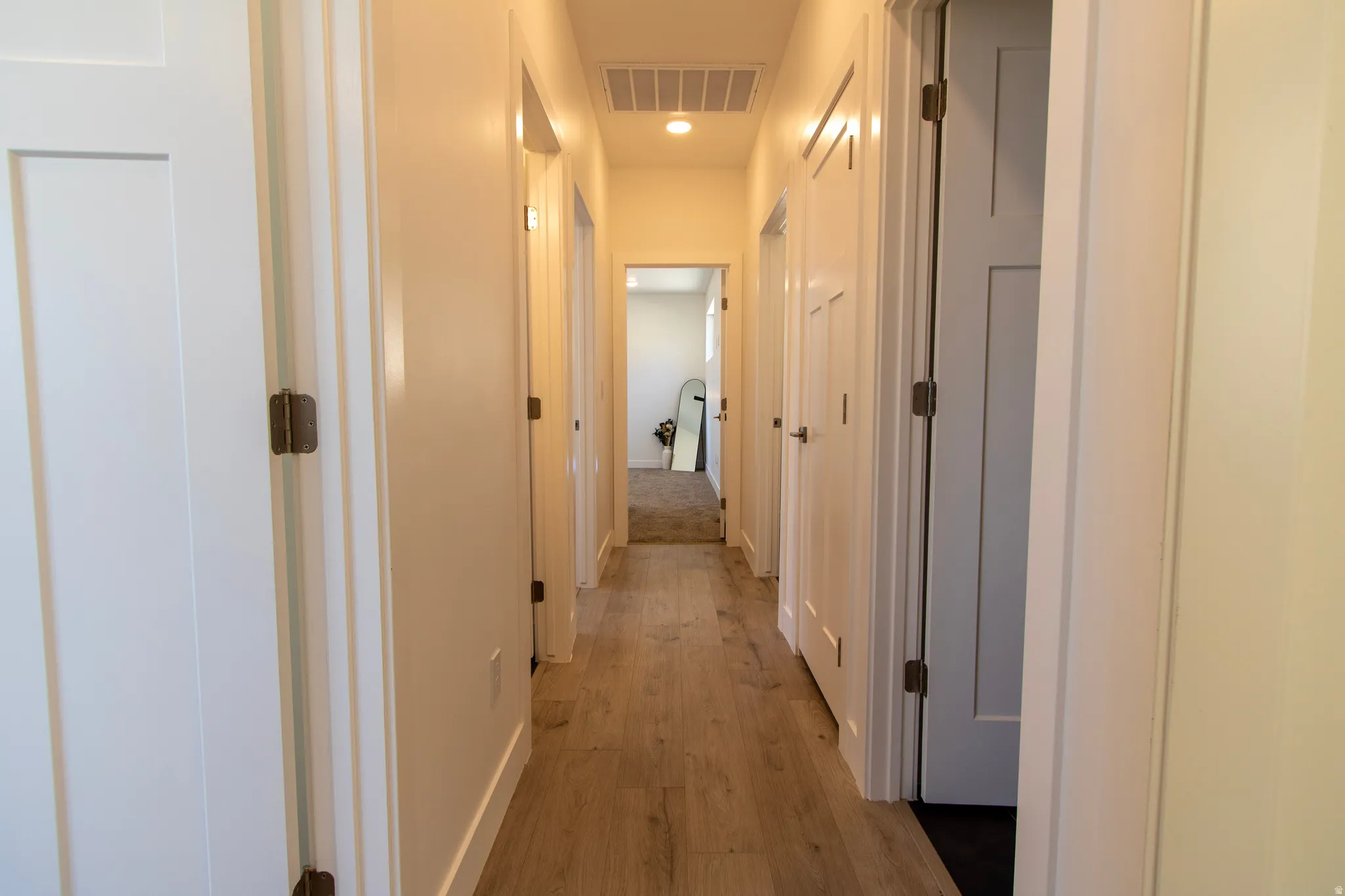 Hallway featuring wood-finish flooring, recessed lighting, and white walls