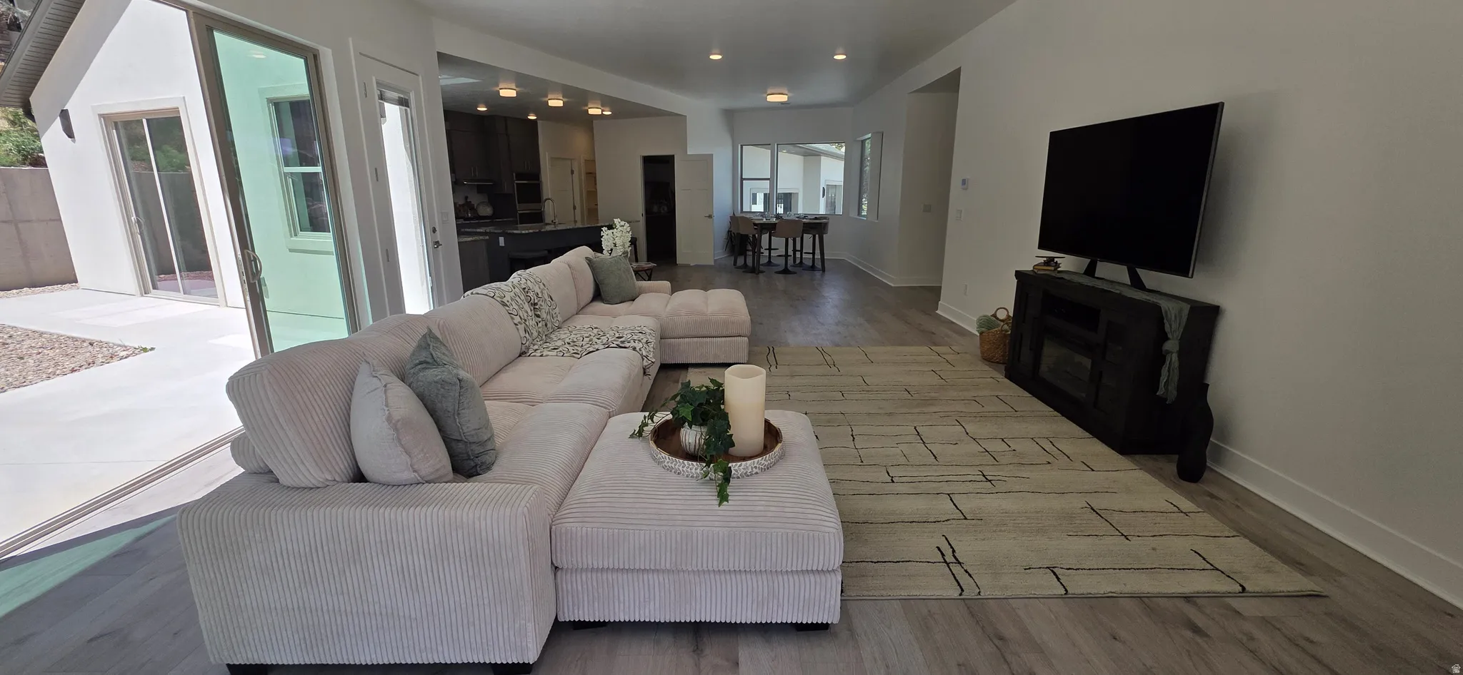 Spacious living area featuring light wood-finish flooring and ample recessed lighting