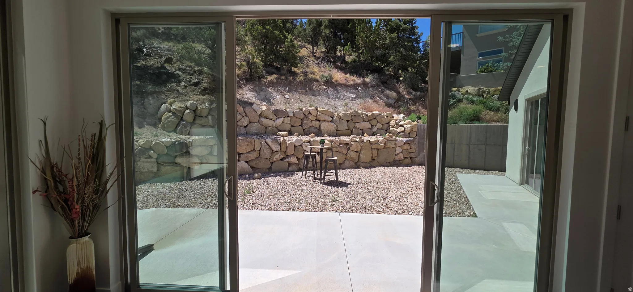 Sliding glass door opening to an outdoor patio with concrete paving and a gravel area