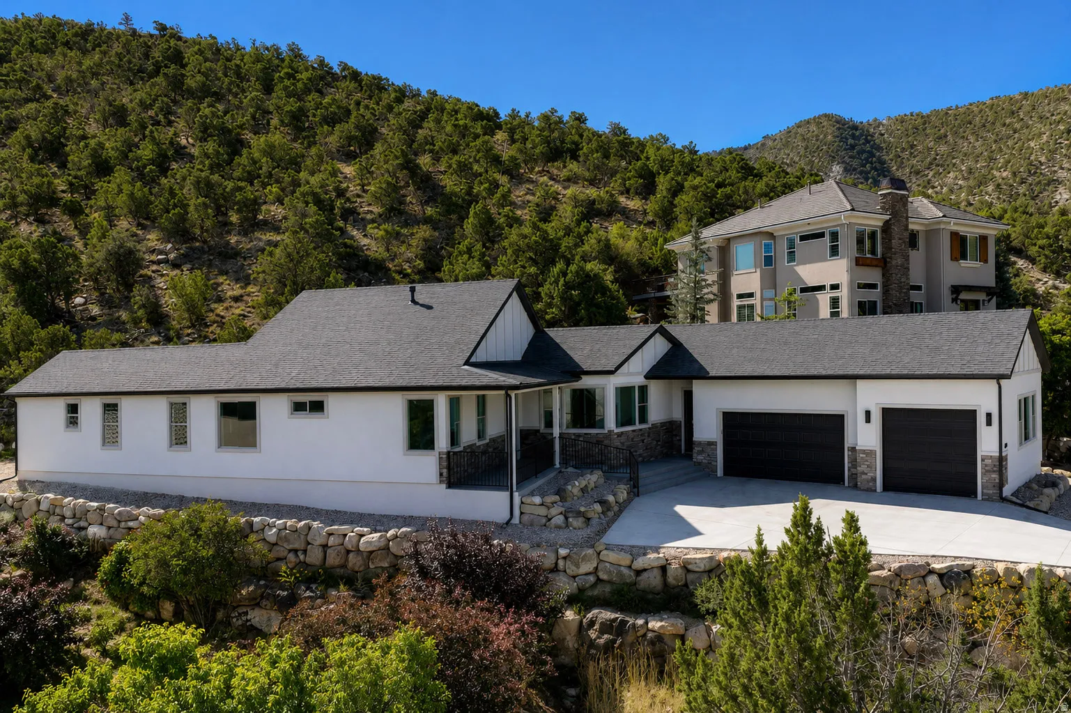 Contemporary residence featuring a white stucco exterior, dark shingle roof, and stone facade accents