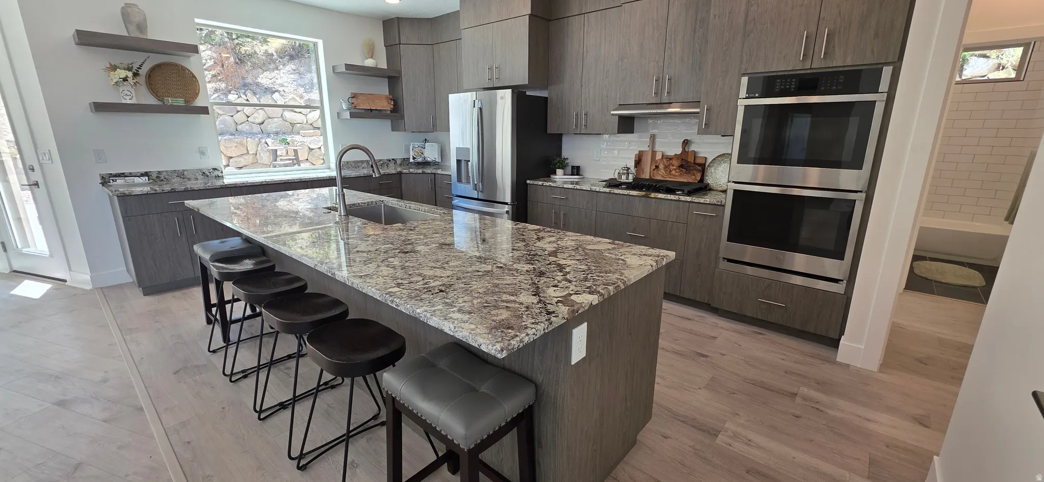 Modern kitchen featuring a large island with a stone countertop, built-in sink, and integrated seating