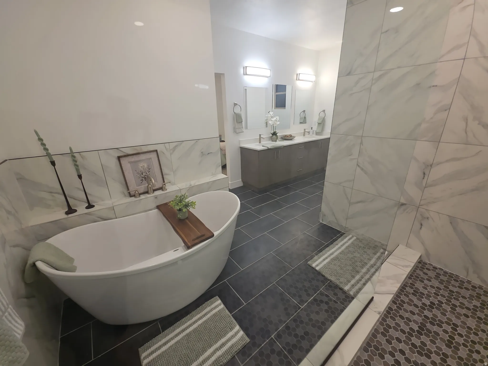 Freestanding soaking tub set against a tiled accent wall