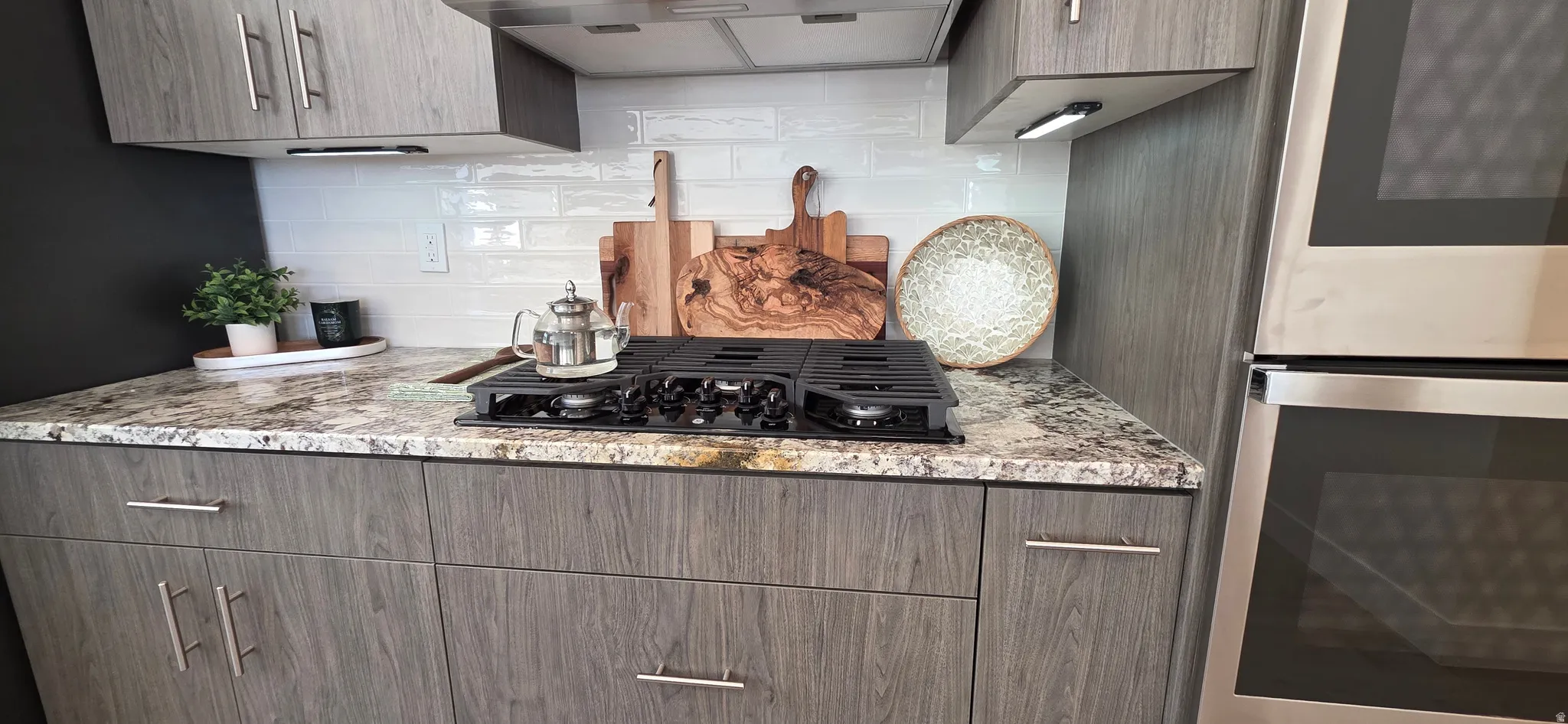 Contemporary kitchen featuring wood-grain cabinetry, a built-in cooktop, and a stainless steel double oven