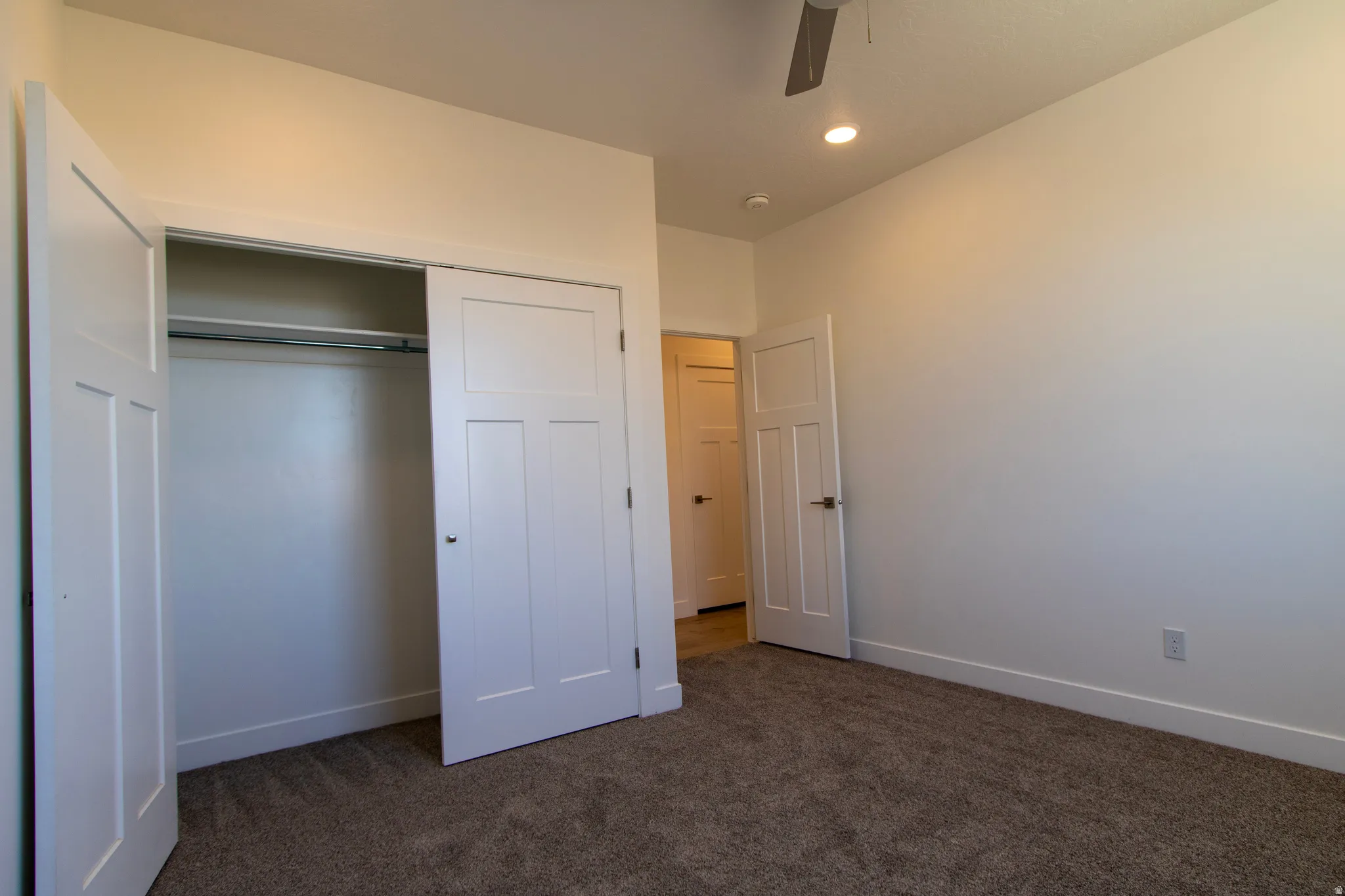 Interior room featuring neutral-toned carpeting, white baseboards, and a contemporary ceiling fan