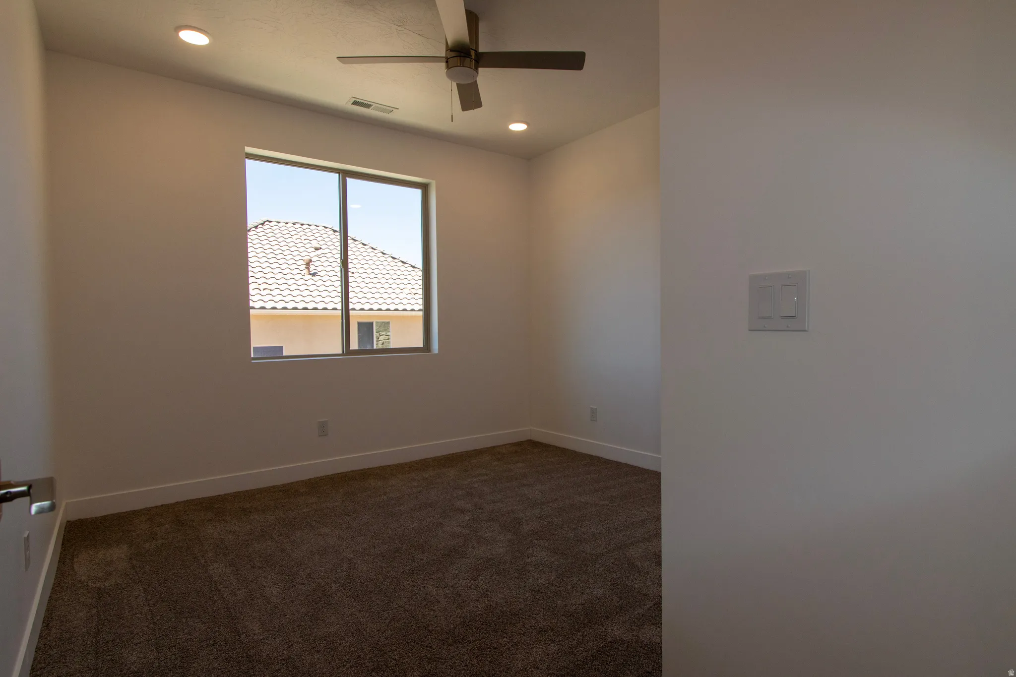 Bright room featuring a large window, neutral carpeting, recessed lighting, and a ceiling fan