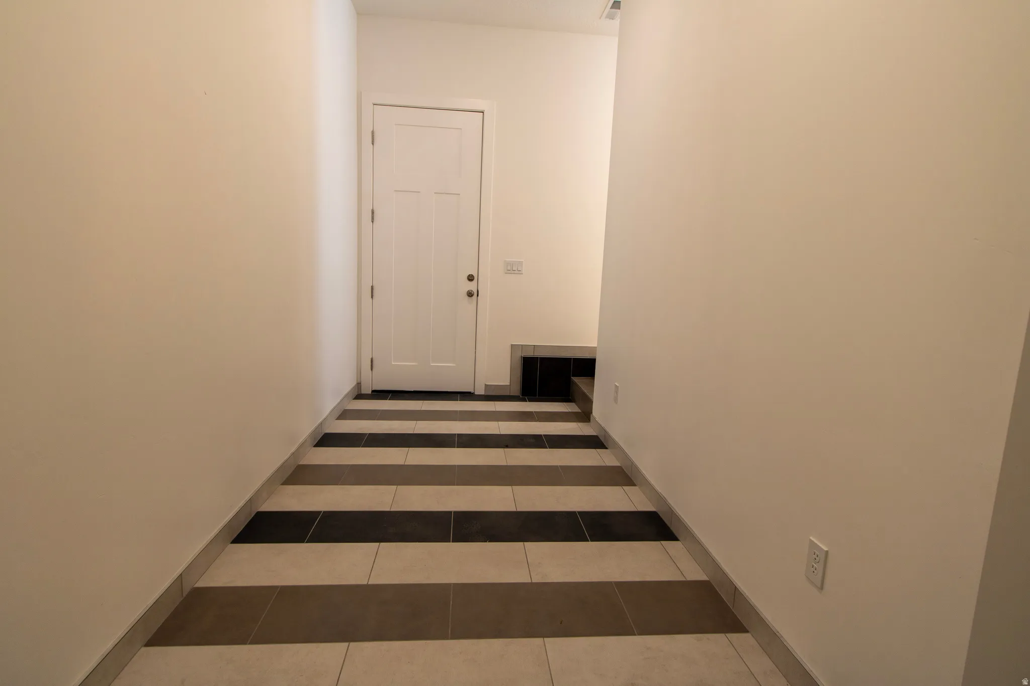Entryway featuring a paneled door, light-toned walls, and multi-toned striped tile flooring