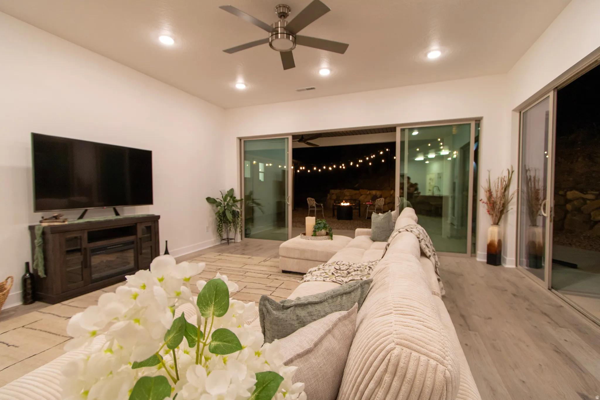 Open-concept living area with recessed lighting and a ceiling fan, featuring a media console with a built-in electric fireplace