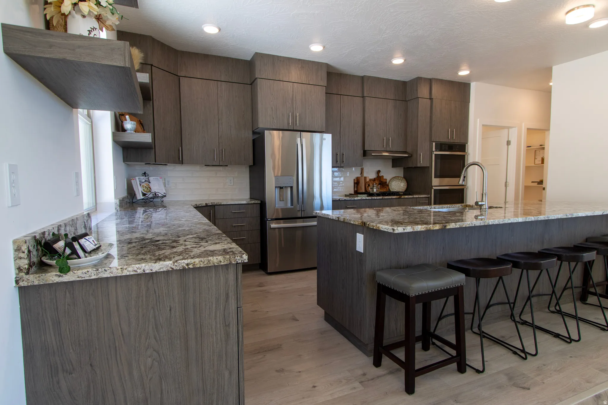 Contemporary kitchen featuring wood-finish cabinetry, granite countertops, stainless steel appliances, a subway tile backsplash, and recessed lighting