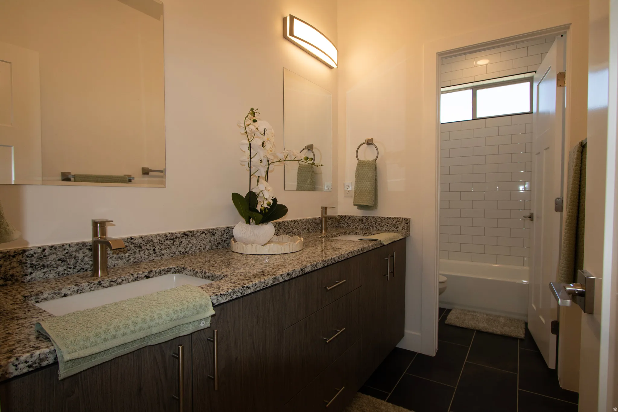 Bathroom vanity featuring a vessel sink, brushed nickel faucet, and granite countertop