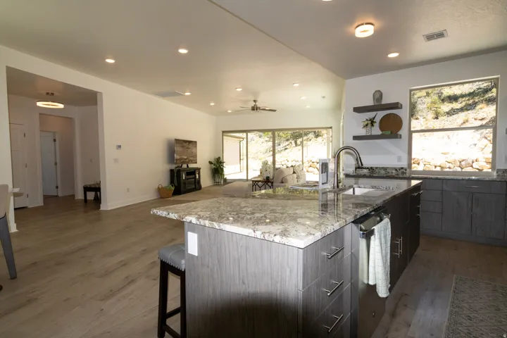Open-concept kitchen and living area featuring a large island with a stone countertop, coordinating cabinetry, wood-finish flooring, and recessed lighting