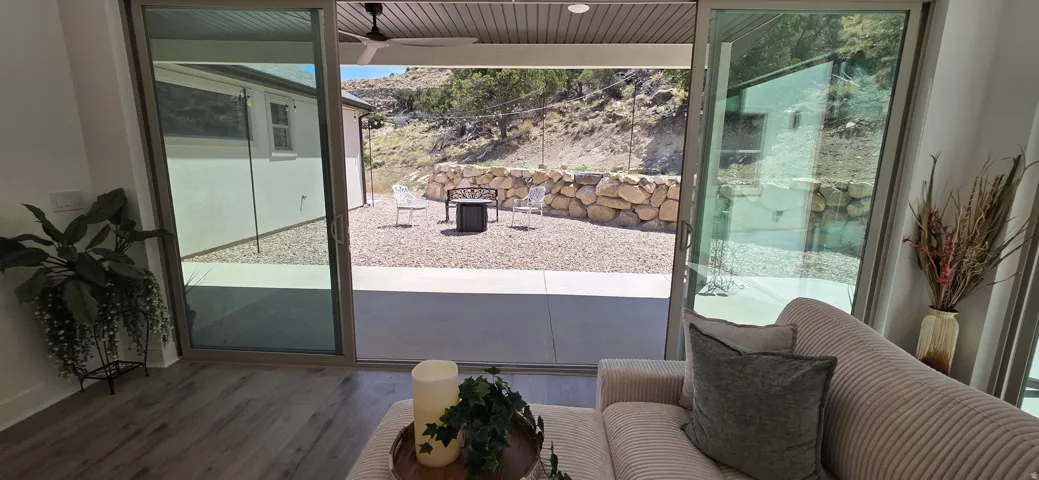 Sliding glass doors opening to an outdoor patio with a gravel hardscape, retaining wall, and natural rock elements