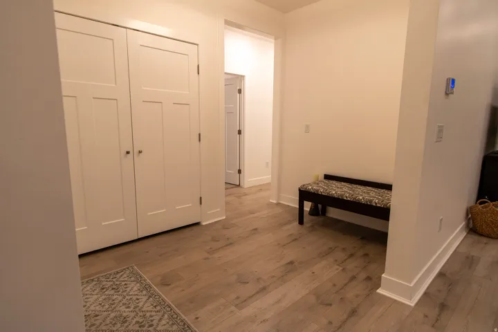 Hallway featuring wood-finish flooring, white trim, and white paneled doors