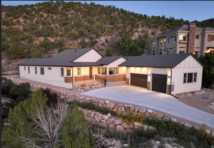 Modern home exterior featuring white siding, dark trim, and stone accents