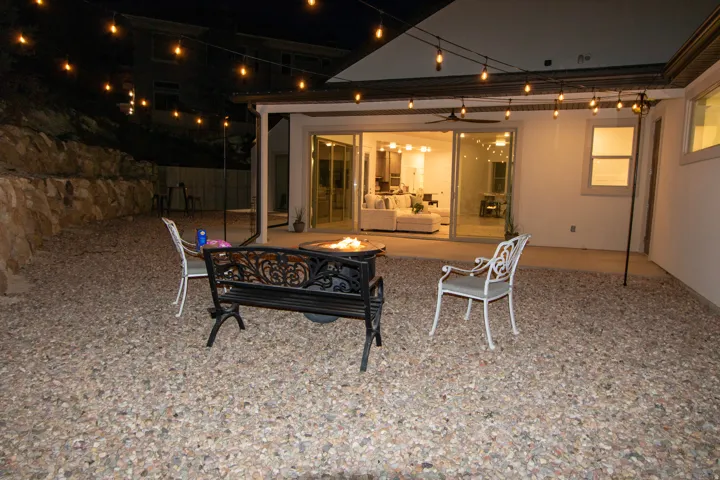 Outdoor entertainment area featuring gravel landscaping, a covered patio, string lighting, and bi-fold glass doors opening to an interior living space