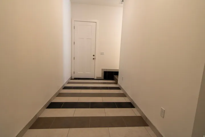 Entryway featuring a paneled door, light-toned walls, and multi-toned striped tile flooring