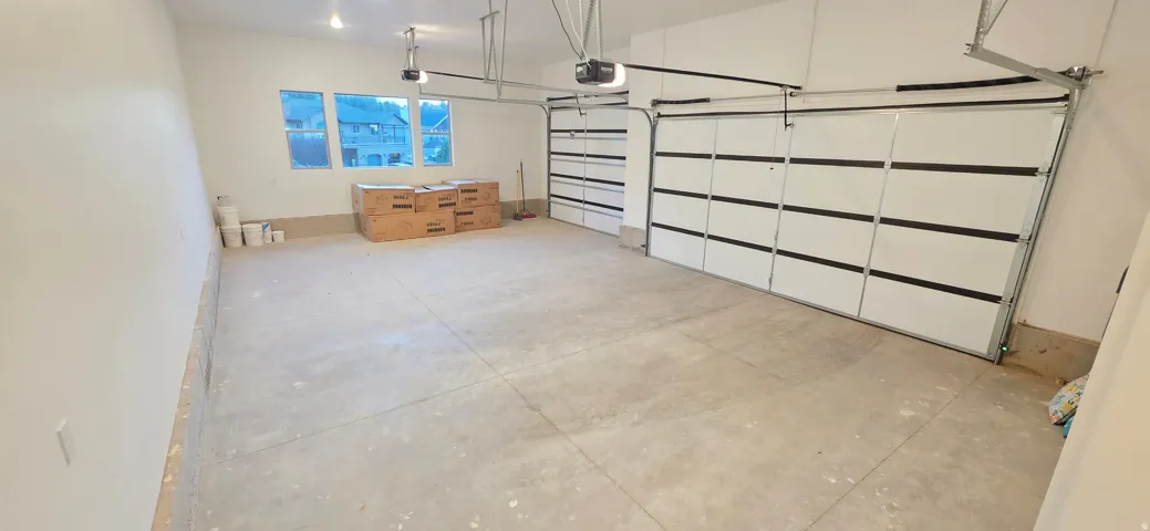 Spacious garage featuring a concrete floor, three large windows, two overhead garage doors, and two garage door openers