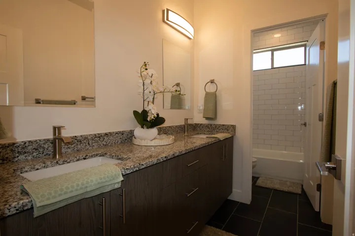 Bathroom vanity featuring a vessel sink, brushed nickel faucet, and granite countertop