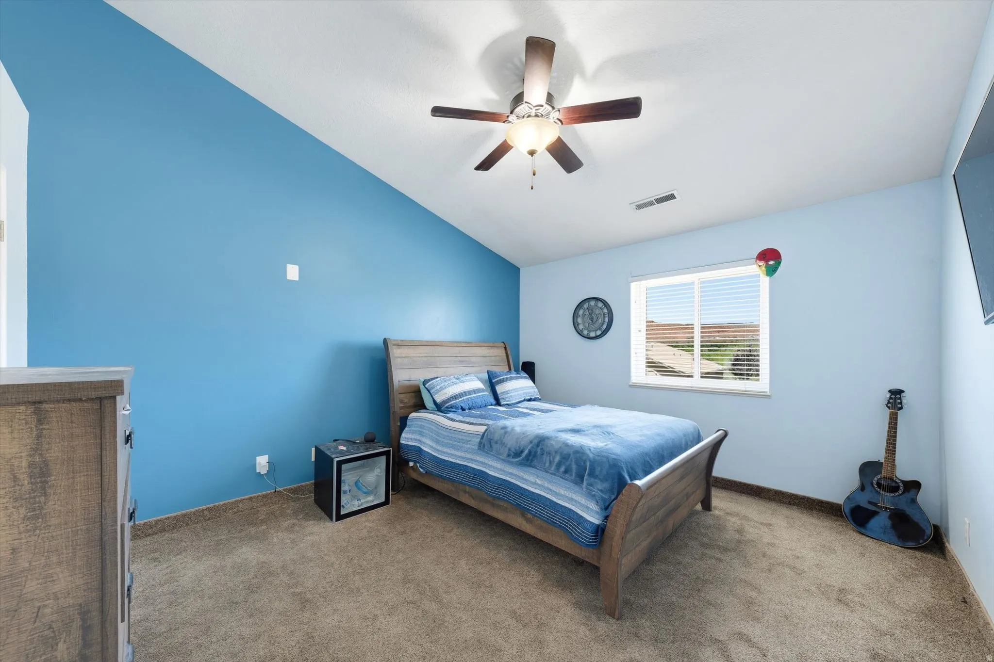 Bedroom featuring an angled accent wall, ceiling fan, carpet flooring, and a single window with horizontal blinds