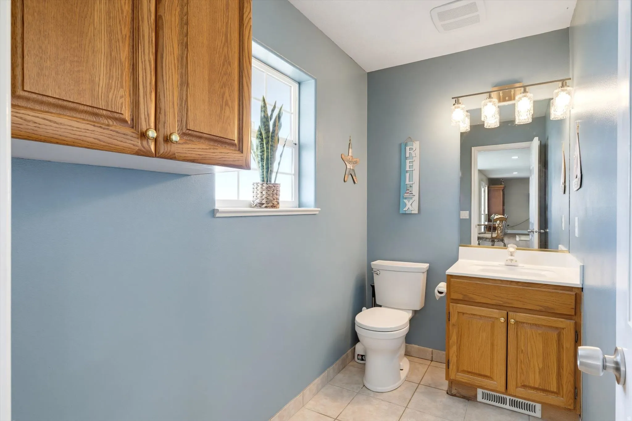 Bathroom featuring a single vanity with wood cabinetry, a white countertop, and an integrated sink