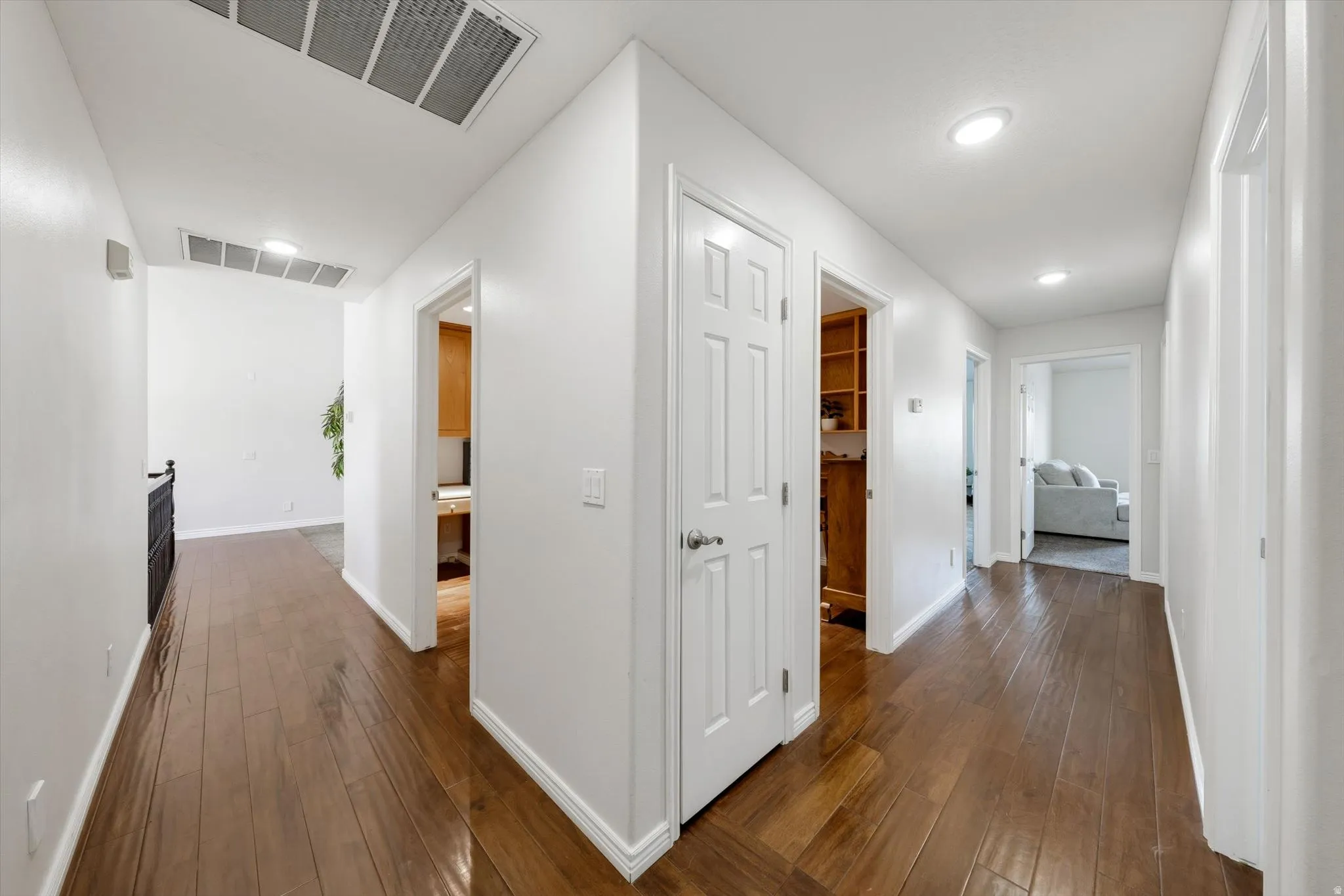 Hallway featuring wood-finish flooring, white walls, recessed lighting, and white baseboards