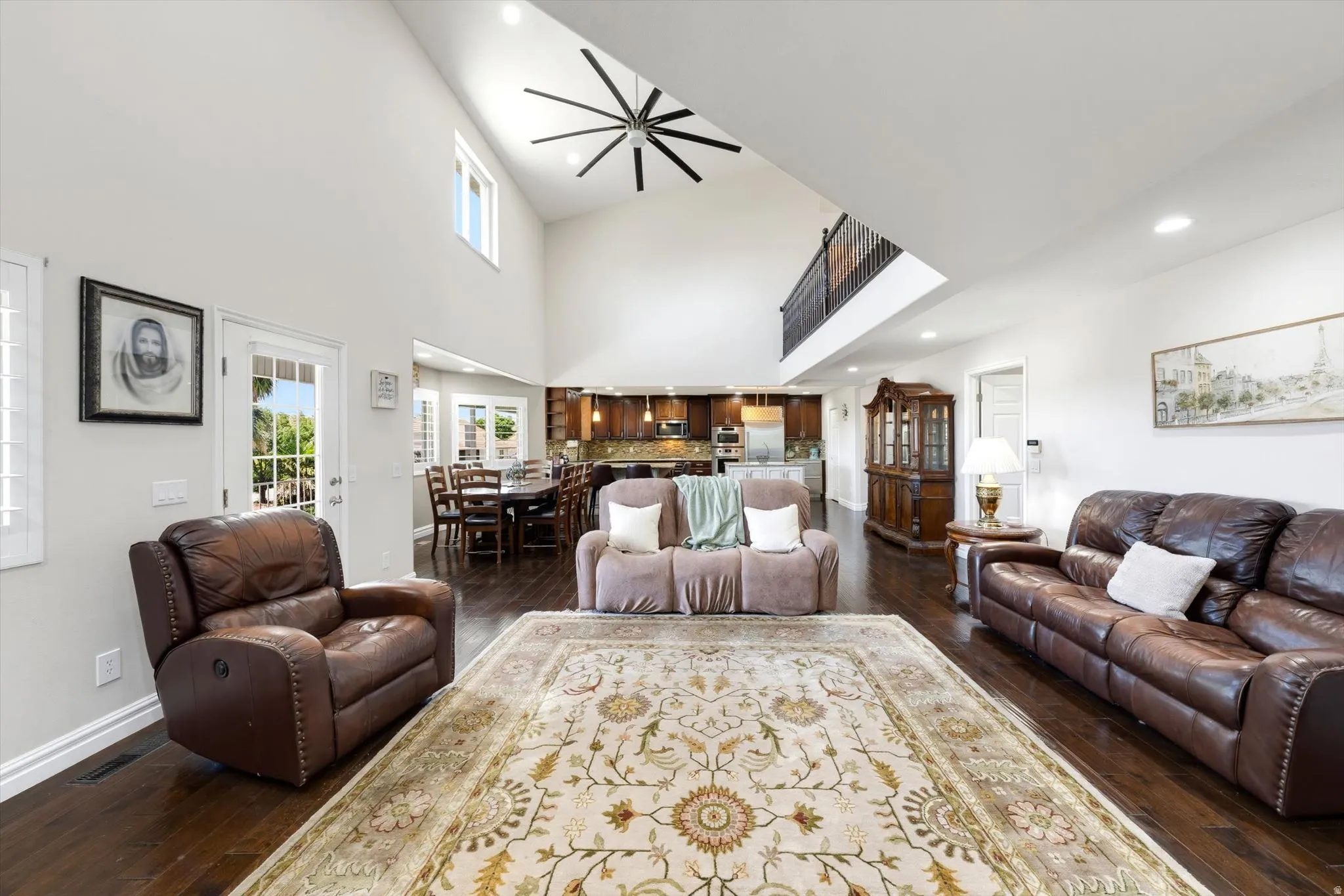 Spacious living area featuring high vaulted ceilings, dark wood-finish flooring, and a large ceiling fan