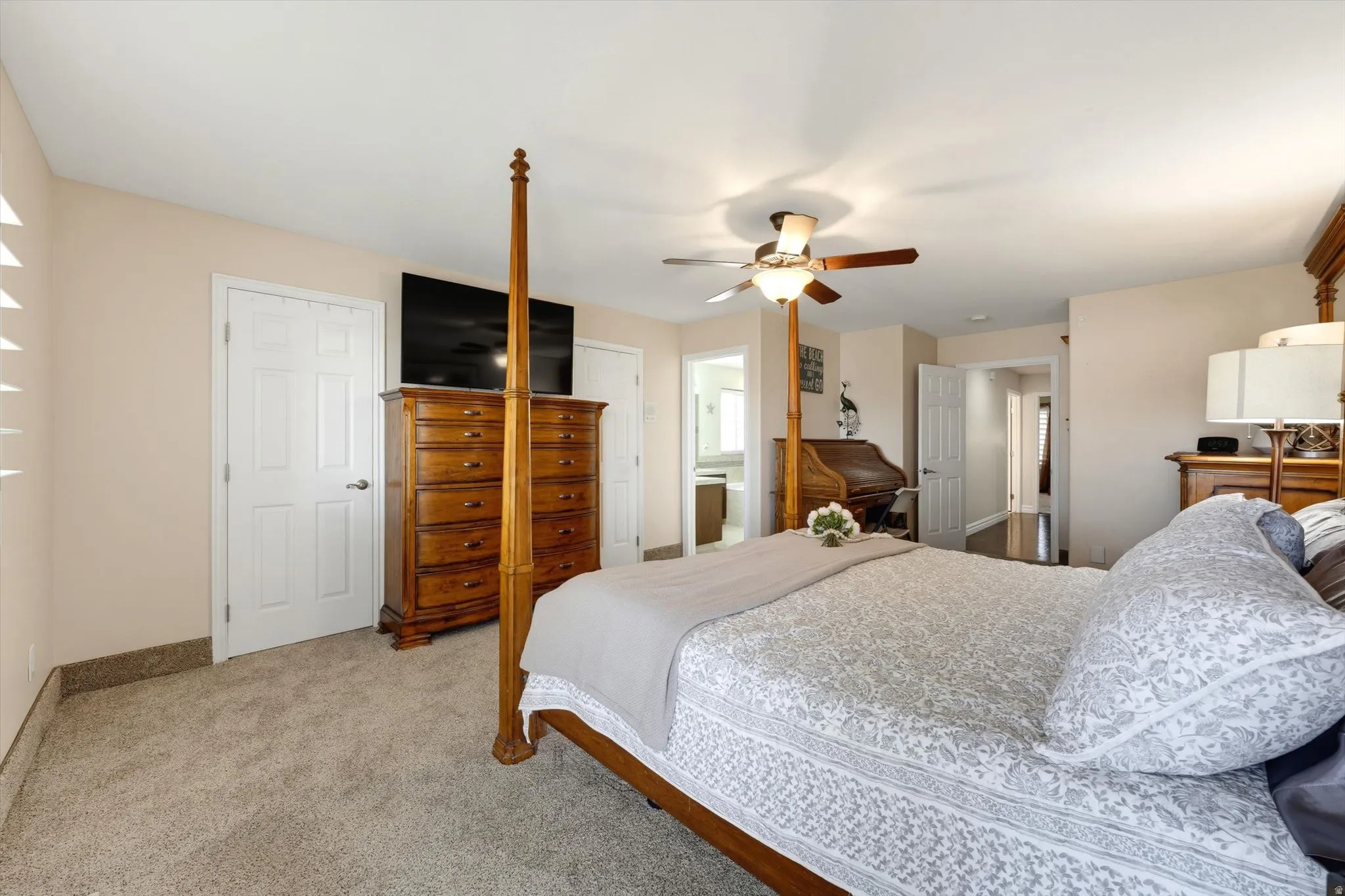 Carpeted bedroom featuring neutral wall tones, a ceiling fan with integrated lighting, and white interior doors