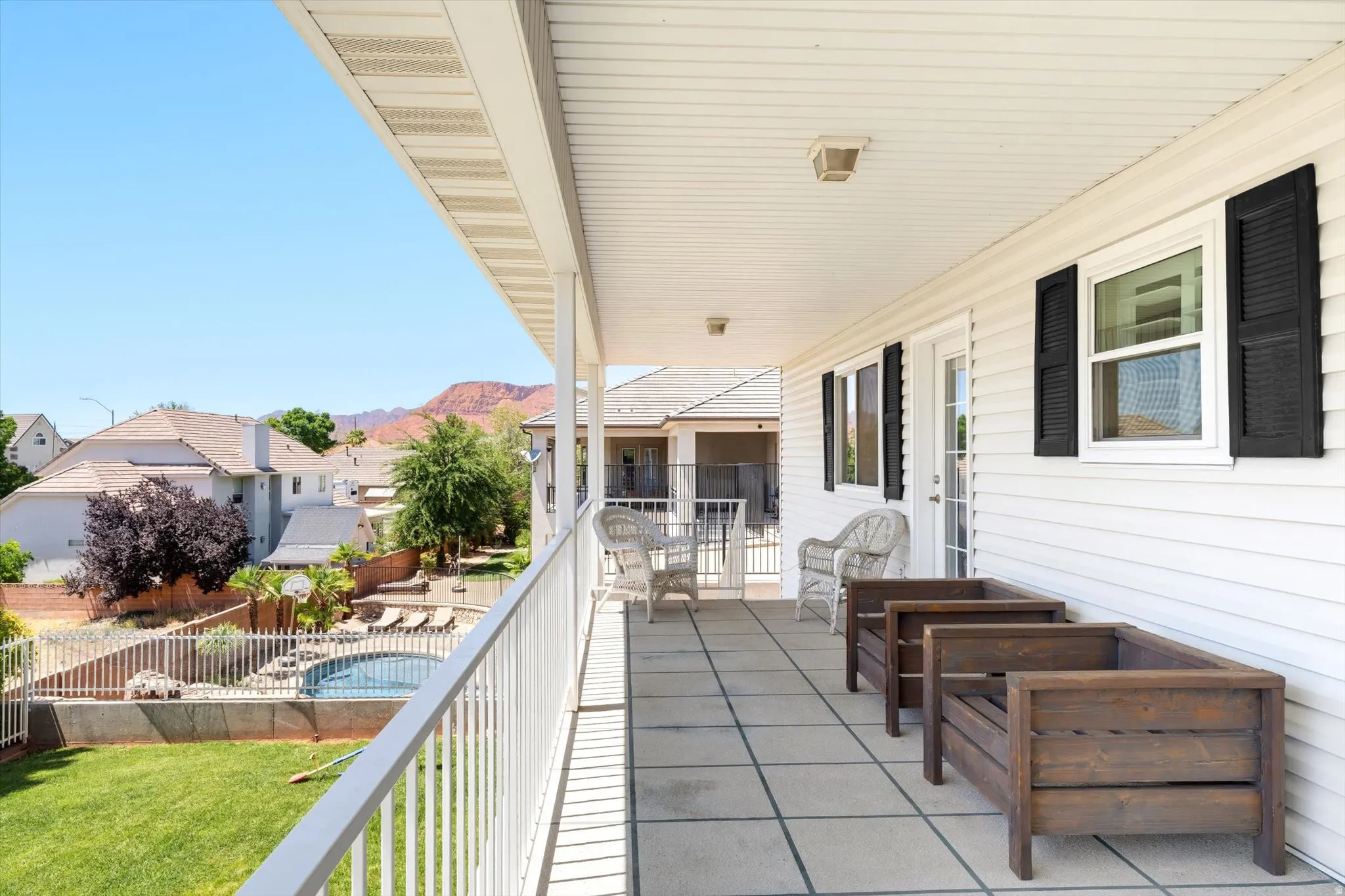 Expansive covered balcony featuring tile flooring and white railing