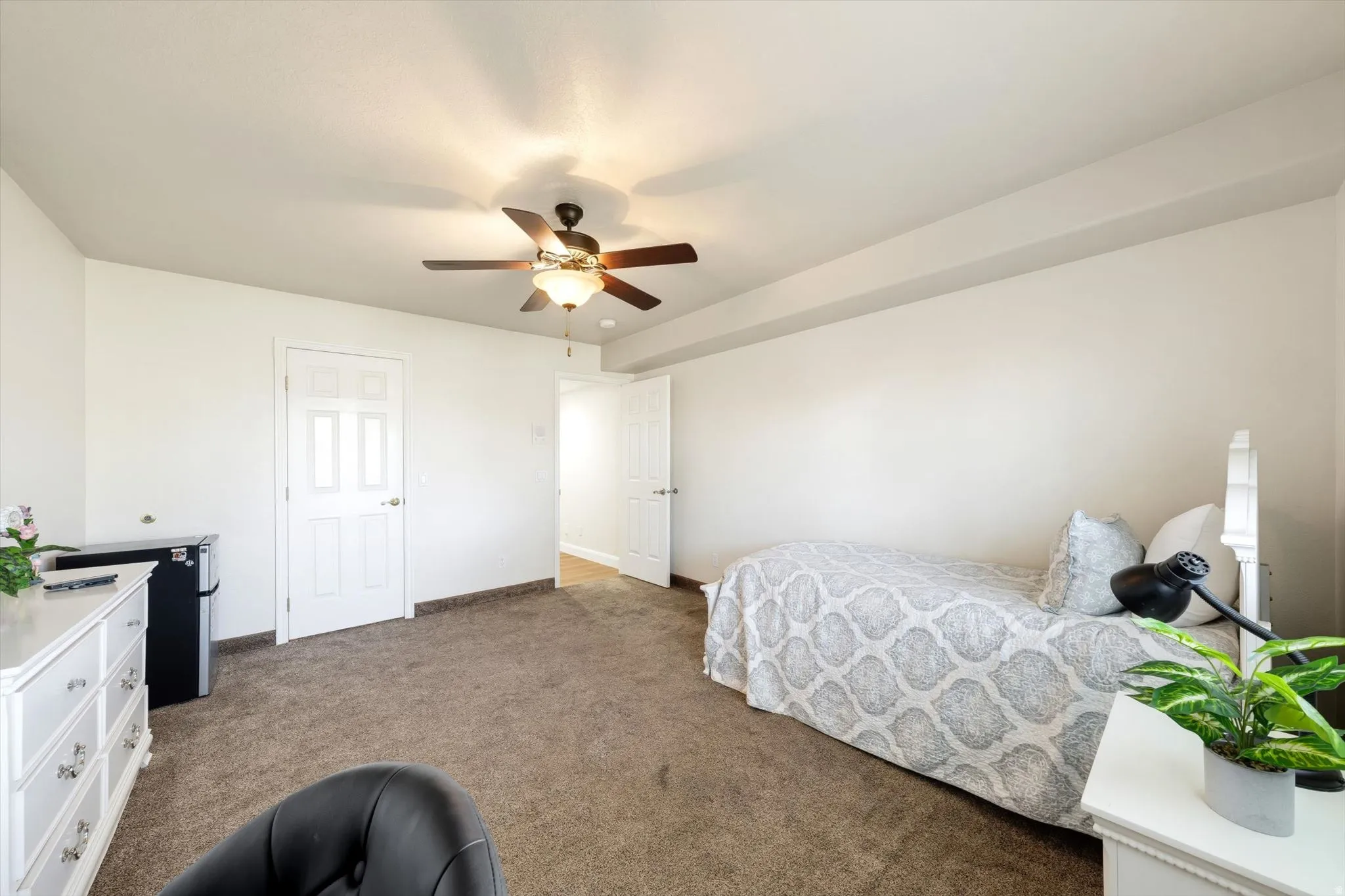 Carpeted room with a ceiling fan, white walls, and white trim