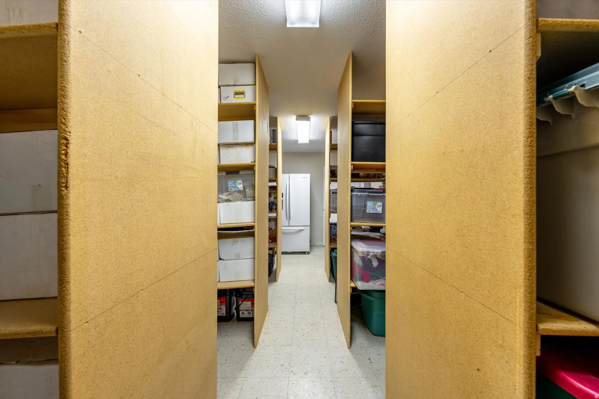 Organized storage area featuring built-in shelving, durable flooring, and recessed lighting