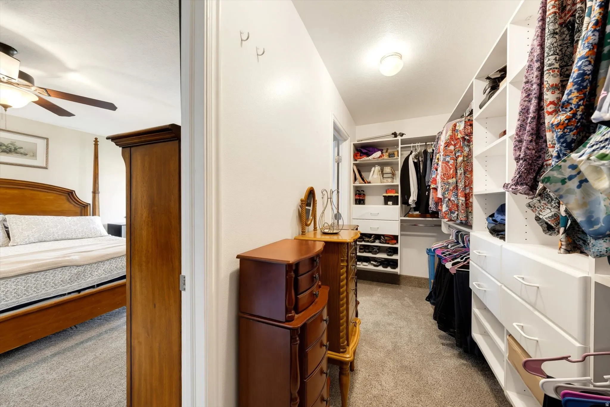 Walk-in closet featuring built-in white shelving, integrated drawers, and ample hanging space