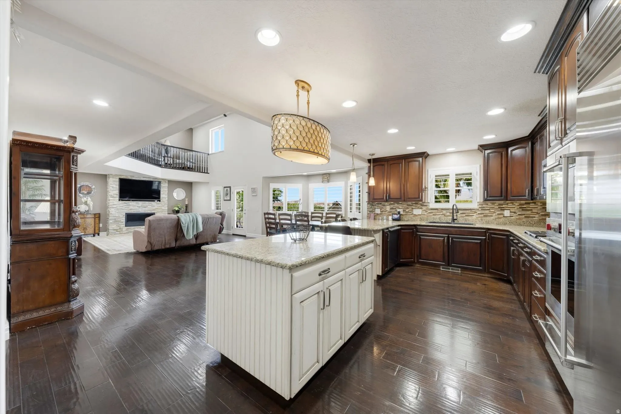 Open-concept living area featuring a kitchen island with white cabinetry, dark wood-finish flooring, and recessed lighting